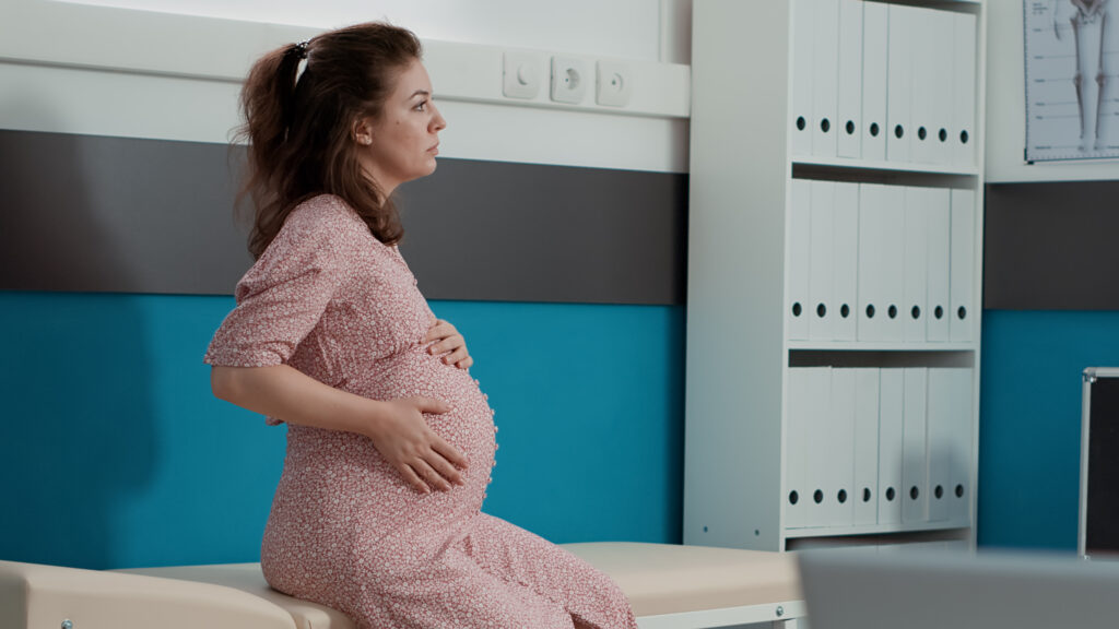 portrait of woman with pregnancy belly waiting to start consultation